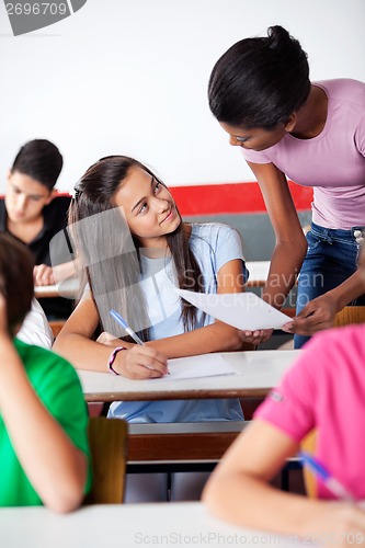 Image of Teacher Assisting Teenage Schoolgirl During Examination In Class