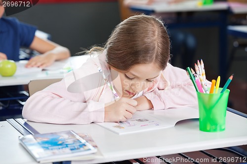 Image of Schoolgirl Drawing In Book At Desk