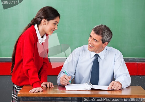 Image of Male Teacher Discussing With Schoolgirl At Desk