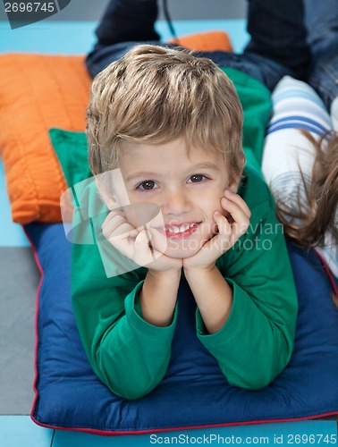 Image of Boy With Head In Hands Lying On Cushions In Kindergarten