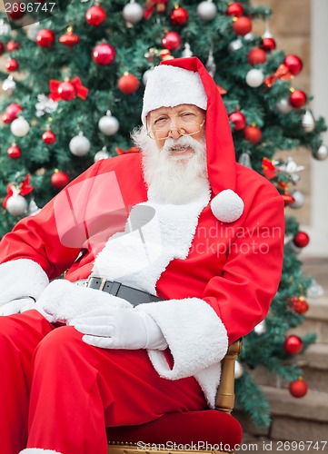 Image of Santa Claus Sitting Against Decorated Christmas Tree