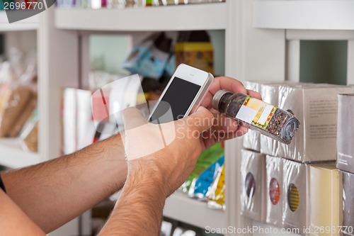 Image of Man's Hand With Cellphone Scanning Product