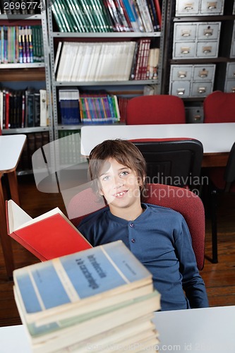 Image of Schoolboy Sitting With Stacked Books At Table