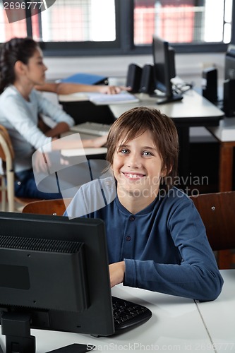Image of Happy Schoolboy Sitting With Computer At Desk