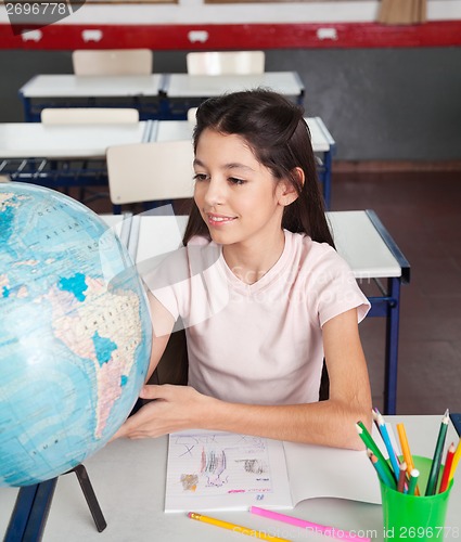 Image of Schoolgirl Searching Places On Globe At Desk