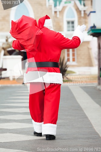 Image of Santa Claus With Bag Waving While Walking In Courtyard
