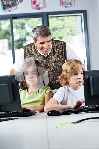 Image of Teacher Looking At Schoolchildren Using Desktop Pc
