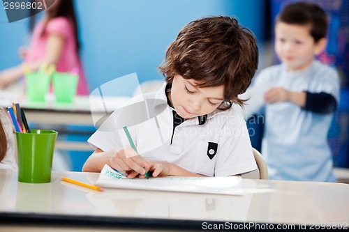 Image of Boy Drawing With Sketch Pen At Desk In Kindergarten