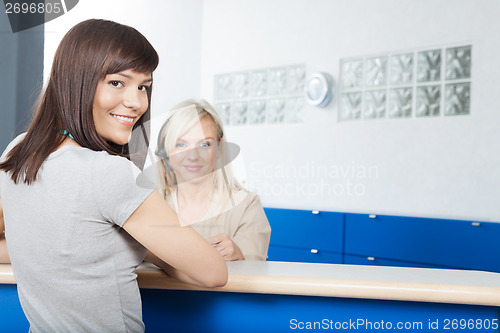 Image of Young Woman With Receptionist At Dentist's Office
