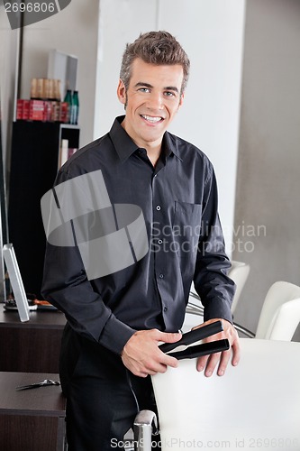 Image of Happy Hairdresser Holding Straightener