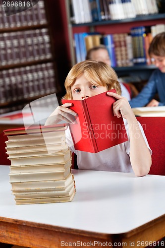 Image of Schoolboy Peeking Through Book In Library