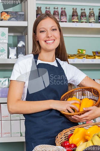 Image of Saleswoman Holding Vegetable Basket In Grocery store