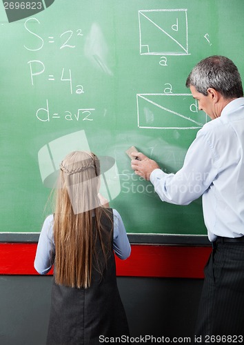 Image of Girl Standing With Teacher Wiping Board