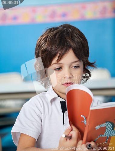 Image of Boy Reading Book In Classroom