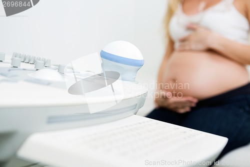 Image of Ultrasound Machine With Pregnant Woman In Background