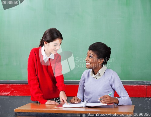 Image of Schoolgirl Pointing On Paper While Teacher Looking At Her