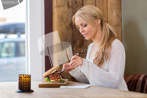 Image of Young Woman Eating Burger At Restaurant