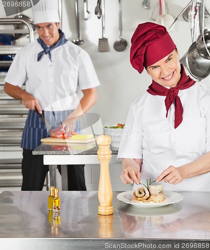 Image of Female Chef Garnishing Dish In Kitchen