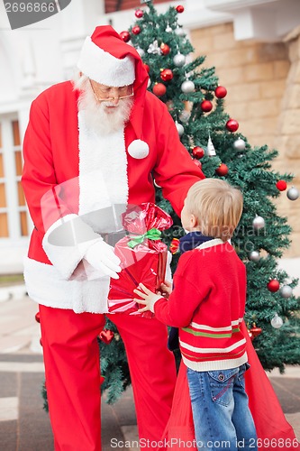 Image of Santa Claus Giving Gift To Boy