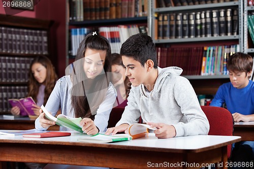 Image of Teenage Classmates Reading Book In Library
