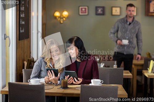 Image of Female Friends Using Digital Tablets At Cafe