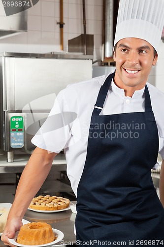 Image of Male Chef Holding Baked Cake In Kitchen