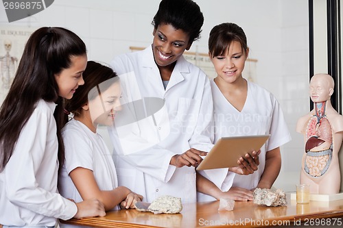 Image of Teacher Looking At Schoolgirls While Using Tablet In Biology Cla