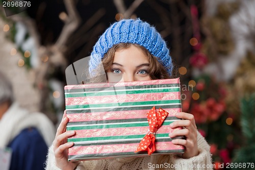 Image of Woman Covering Face With Christmas Present At Store