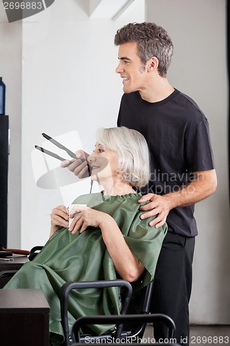 Image of Woman With Coffee Cup And Hairdresser Holding Straightener