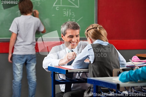 Image of Professor Assisting Schoolgirl At Desk