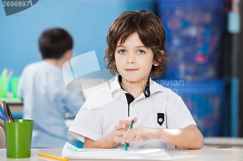 Image of Cute Boy With Paper And Sketch Pen At Desk