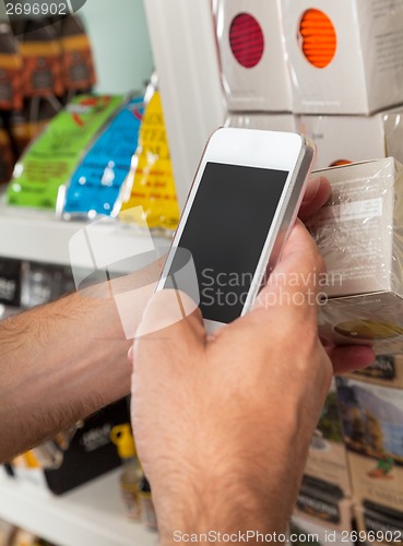 Image of Man's Hand With Smart Phone Scanning Product