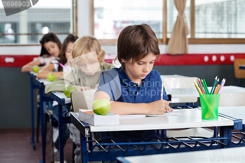 Image of Schoolchildren Writing In Books At Desk