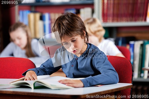 Image of Schoolboy Reading Book At Table In Library