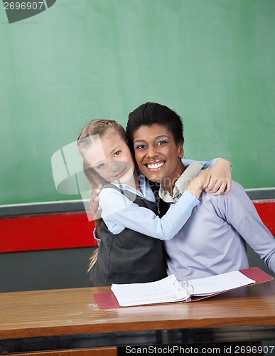 Image of Schoolgirl Hugging Professor At Desk