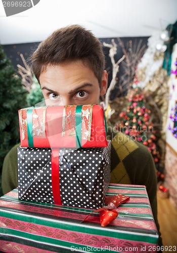 Image of Man Looking Over Stacked Christmas Gifts In Store