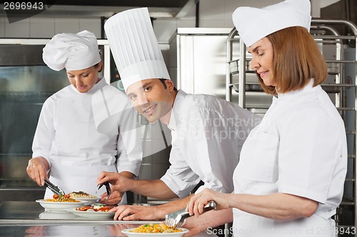 Image of Male Chef With Colleagues Working In Kitchen