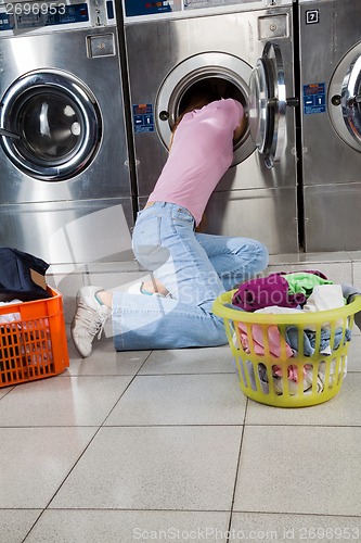 Image of Woman Searching Clothes In Washing Machine Drum