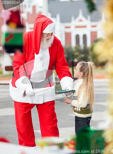 Image of Santa Claus Offering Cookies To Girl