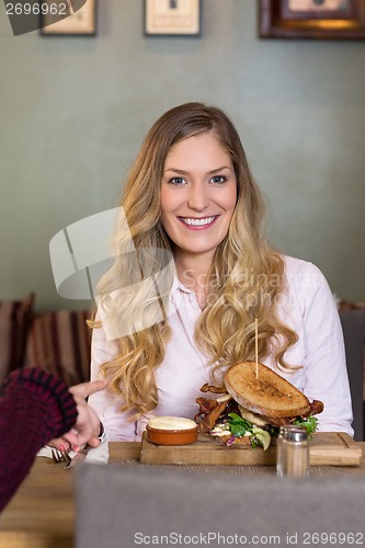 Image of Young Woman With Burger At Table