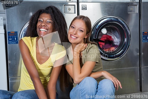 Image of Female Friends Sitting Together At Laundry