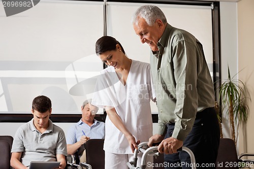 Image of Man Being Assisted By Nurse To Walk Zimmer Frame