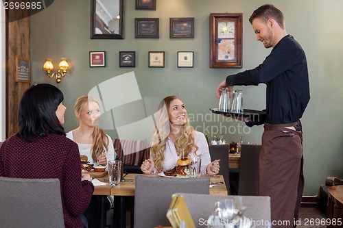 Image of Waiter With Tray Of Glasses While Female Customers Having Meal