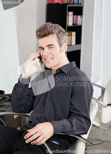 Image of Male Customer Using Cellphone At Salon