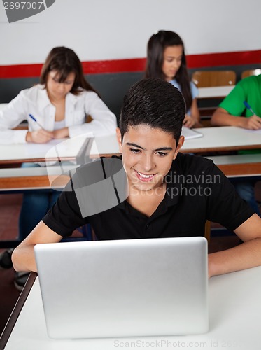 Image of Happy Teenage Schoolboy Using Laptop