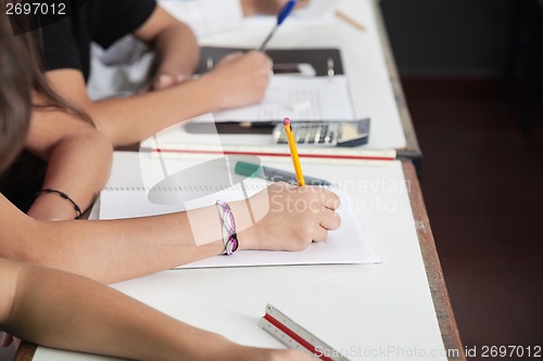 Image of Midsection Of Schoolchildren Writing At Desk