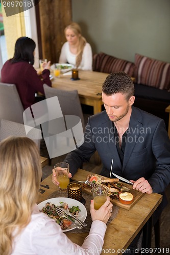 Image of Businessman Eating Food With Female