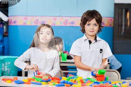 Image of Cute Friends Playing With Blocks At Desk In Kindergarten