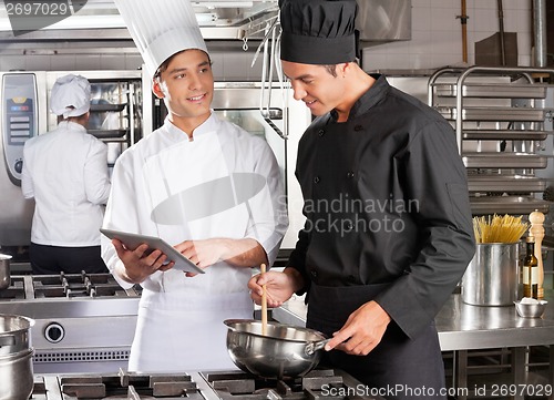 Image of Male Chef Assisting Colleague In Preparing Food