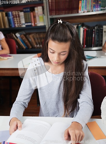 Image of Female Student Reading Book At Table In Library